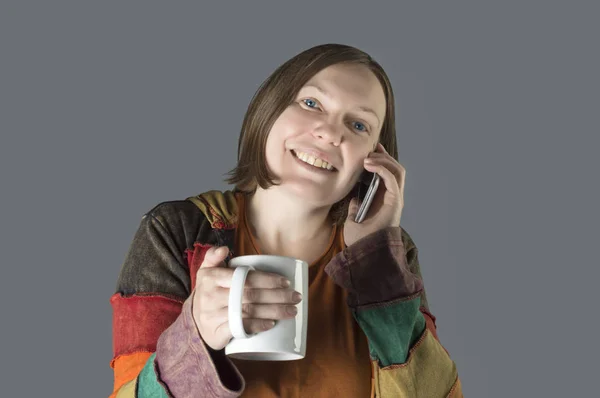 Woman talking on her mobile and holding cup of tea. — Stock Photo, Image