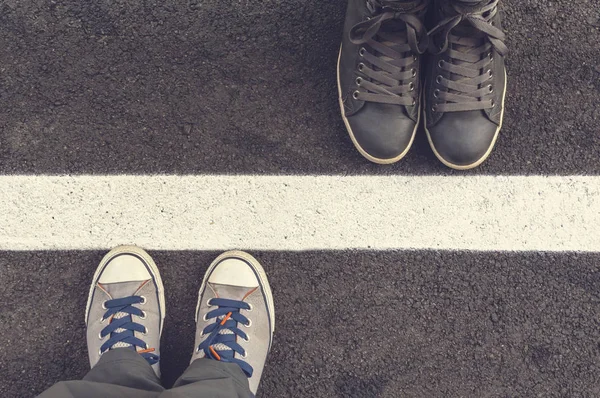 Two pair of sneakers on a asphapt road. — Stock Photo, Image