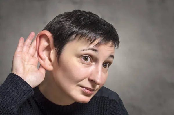 Seriös kvinna med ett stort öra lyssnar uppmärksamt — Stockfoto