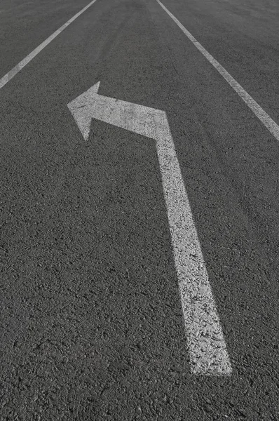 Girare a sinistra freccia bianca segno sulla strada . — Foto Stock