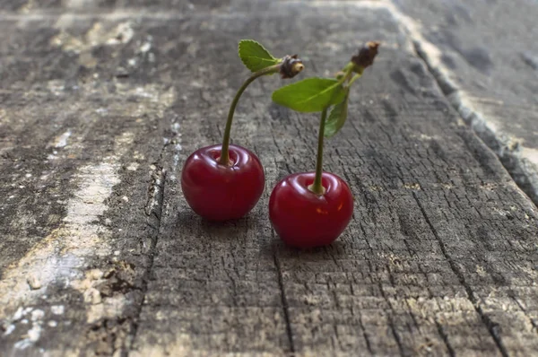 Dvě červené třešně na starý dřevěný stůl. — Stock fotografie
