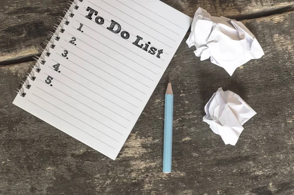 Lista de tareas en un cuaderno con lápiz papel arrugado sobre una mesa de madera —  Fotos de Stock