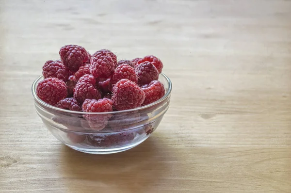 Framboises dans un bocal en verre sur une table en bois . — Photo