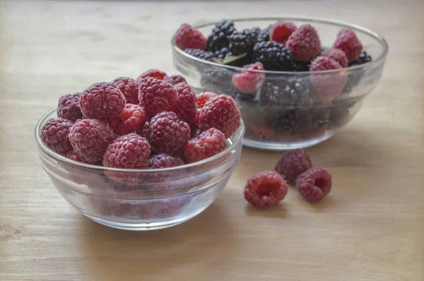 Raspberries and blackberries in a glass jar on a wooden table. — Stock Photo, Image