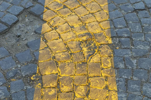 Textuur van donker grijze keien met gele lijn — Stockfoto