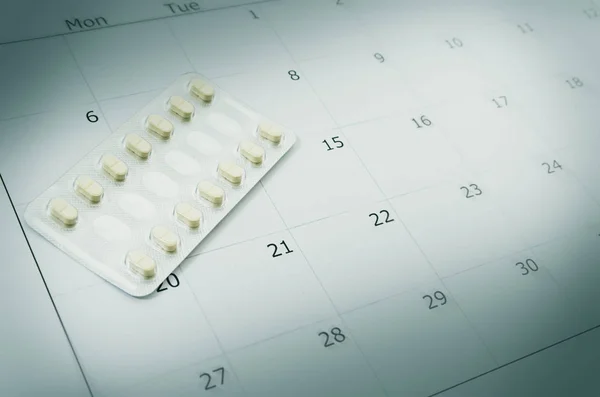 Fechar pílula anticoncepcional com data de fundo do calendário, ele — Fotografia de Stock
