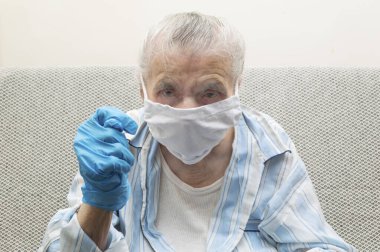 Tıbbi maskeli ve incir işareti gösteren elini kaldırmış yaşlı bir kadın. Covid-19 virüs salgını ve dünya çapında salgınla savaşmak için bir işaret gösteriyor. Coronavirus reddetme konsepti