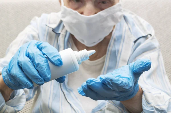 手の消毒やウイルス対策の概念 高齢女性は ボトルからアルコールを絞るゴム手袋で手を消毒 — ストック写真
