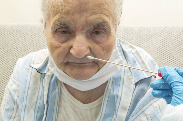 Coronavirus test - Medical worker taking a throat swab for coronavirus sample from a potentially infected elderly women 