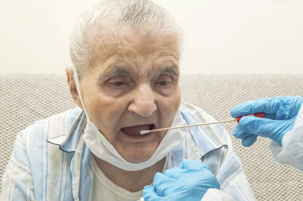 结肠病毒测试 医务工作者从可能感染的老年妇女的喉咙中取出结肠病毒样本 图库图片