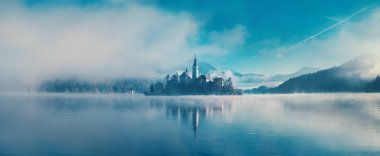Amazing view on a misty morning of lake Bled with St. Marys Church of the Assumption on the small island; Bled, Slovenia, Europe.