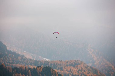 Dolomitlerle, İtalya 'da dağların üzerinden uçan paraglider. Güneşli bir sonbahar günü.