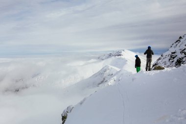 Kayakçılar dağın tepesinden güzel karlı manzaraya bakıyor. Arka planda Yüksek Tatra dağları. Chopok Peak, Low Tatras, Slovakya, Avrupa.