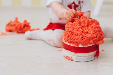 Little girl smashing cake with her hands on her first birthday, making a mess clipart
