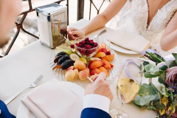 Νύφη και γαμπρός νιόπαντροι τρώνε φρούτα και πίνουν σαμπάνια την ημέρα του γάμου τους — Φωτογραφία Αρχείου