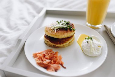 Besleyici ve lezzetli kahvaltıyı tepside yatakta yakın.