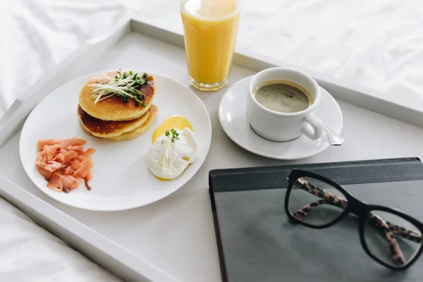 Close up of nutritious and tasty breakfast with coffee in bed on tray with glasses and book — 스톡 사진