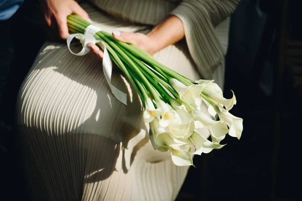 Mulher em pastel ou vestido de marfim segurando um belo buquê de flores de lírio calla — Fotografia de Stock