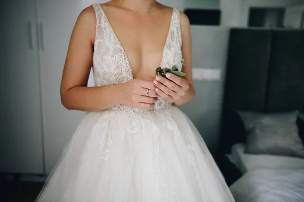 Novia caucásica sosteniendo un delicado boutonniere de flores en el día de su boda vistiendo hermoso vestido revelador — Foto de Stock