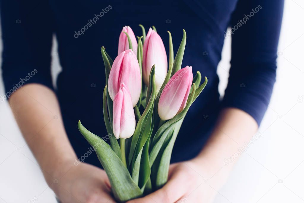 Close up of hands of young caucasian woman holding a bouquet of spring tulips. 