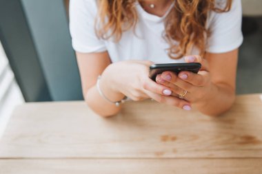 Genç beyaz kadın telefonunda sosyal medya kullanıyor ya da mesajlaşıyor.