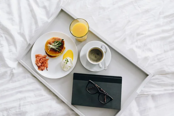 안경 과 책의 맨 위 뷰가 달린 트레이 위에 놓인 커피와 함께 영양있고 맛있는 아침 식사 — 스톡 사진