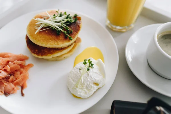 Close up de panquecas saudáveis nutritivas e saborosas e café da manhã ovo escalfado na cama na bandeja — Fotografia de Stock