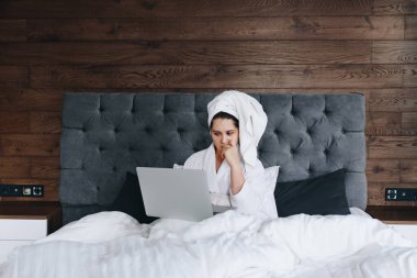 Genç Kafkas iş kadını Coronavirus yüzünden karantina sırasında laptopuyla yatağında çalışıyor.