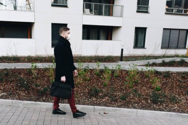 Genç yakışıklı adam covid-19 koronavirüs salgını sırasında bir yerleşim bölgesinde yürüyor.