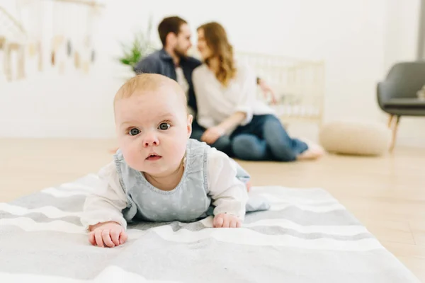 Caucásico bebé arrastrándose en el suelo de la guardería con sus padres en el fondo — Foto de Stock