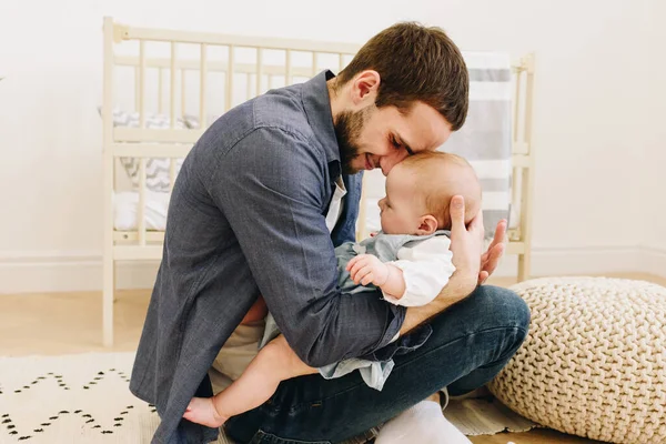 Joven padre con su bebé en la guardería, sosteniéndola suavemente — Foto de Stock