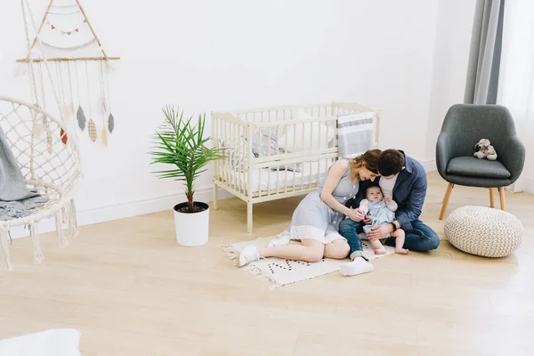 Hermosa familia caucásica de madre, padre y su bebé del suelo el vivero — Foto de Stock