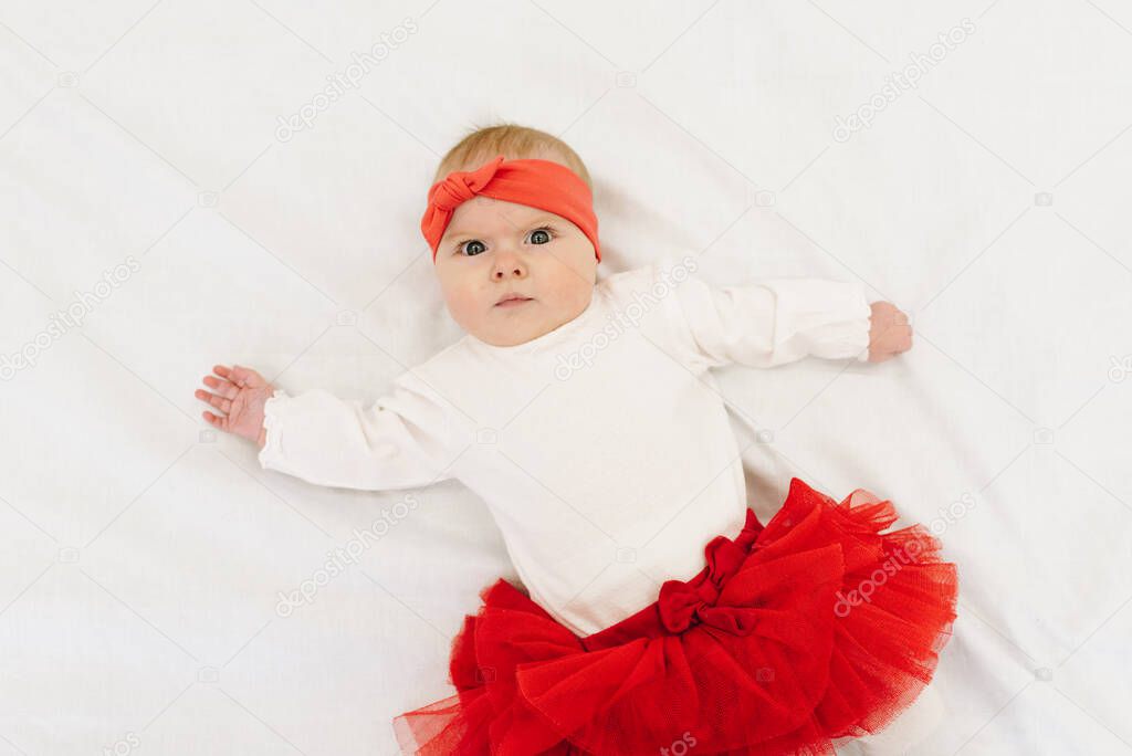 Very cute caucasian baby girl wearing red skirt and matching headband