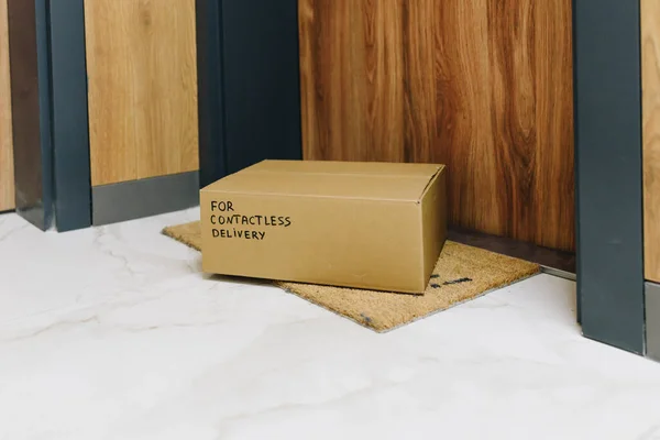 Box delivered via contactless delivery on doormat in front of front door, parcel ordered online during global coronavirus covid-19 infection pandemic as digital transformation changes e-commerce