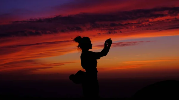 Girl takes a selfie at sunset. Silhouettes of the girl. Young, beautiful, girl photographs herself on a sunset background. Sea walk. Travel, photography at the ends of the world. Sunset in Portugal. The magic of evening sunset.