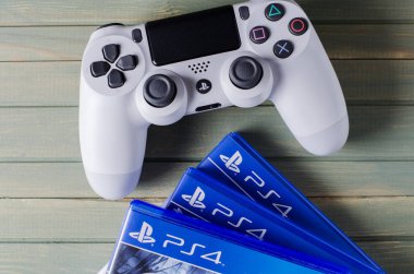 İzhevsk, Rusya - 17 Ekim 2019: Beyaz joystick oyun konsolu Playstation. Çoklu Ps4 oyunu. Mavi tahta arkaplan.
