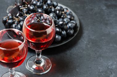 Bardakta kırmızı şarap, bir demet siyah üzüm. Karanlık arka plan. Kopyalama alanı