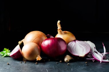 Gri beton bir masada soğanlar. Siyah arka plan. Yan görünüm.