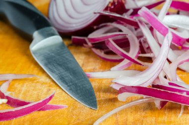 Kırmızı soğan, dilimlenmiş ve mutfak bıçağı yakın plan. Tahta kesim tahtası