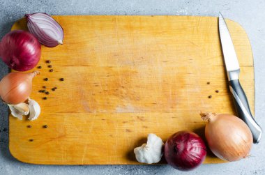 Sarı tahta kesim tahtası. Soğan, mutfak bıçağı ve baharatlar. Boşluğu kopyala