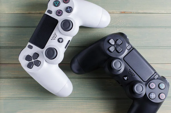 İzhevsk, Rusya - 17 Ekim 2019: Siyah ve beyaz joystickler oyun konsolu Playstation. Mavi tahta arkaplan