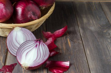 Hasır sepette kırmızı soğan. Taze hasat. Kahverengi ahşap arka plan