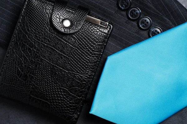 Blue mens necktie, jacket sleeve, and black wallet. Concept image of a successful business man