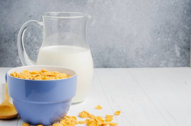 Bardakta mısır gevreği ve süt. Beyaz ahşap masa. Boşluğu kopyala
