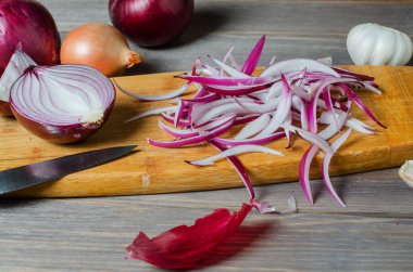 Kırmızı soğan dilimlenmiş. Sarı kesim tahtasında pişirme işlemi