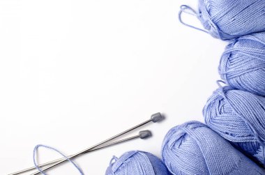 Mavi iplik ve örgü iğnelerinden oluşan toplar. Beyaz arka plan. Uzayı kopyala Kadın nakış işi konsepti..