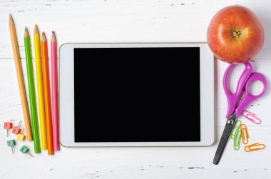 Boş ekranlı bir tablet ve beyaz ahşap arka planda ofis malzemeleri. Okul çocukları için konsept uygulama ya da çocuklar için çevrimiçi öğrenme. Boşluğu kopyala