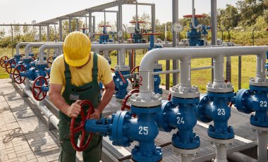 İşçi gaz işleme tesisinde valf çeviriyor.
