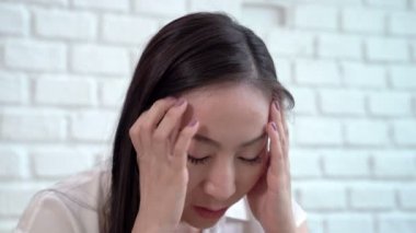 Asyalı orta yaşlı kadınlar umutsuzca baş ağrısı çekerek başlarından tutarlar..