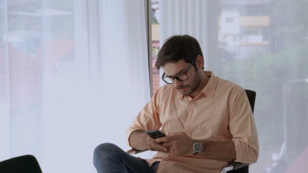 Yakışıklı Beyaz Adam Rahat Bir Şekilde Cep Telefonu Kullanarak Oturmuş — Stok video